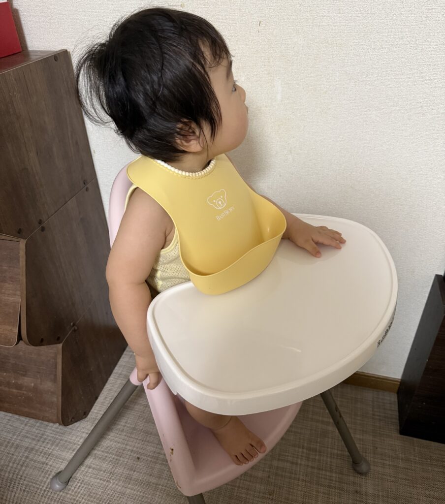 ハイチェアに座っている食事エプロンをつけた赤ちゃん